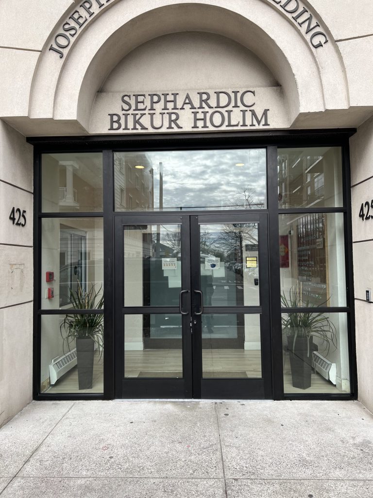 Sephardic Bikur Cholim building entrance with glass doors, potted plants, and address 425.