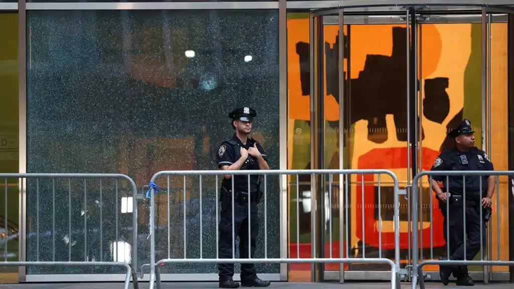 Police officers stand next to the glass window with a bullet hole near the scene of a deadly mass shooting in Manhattan, New York City on July 29, 2025.