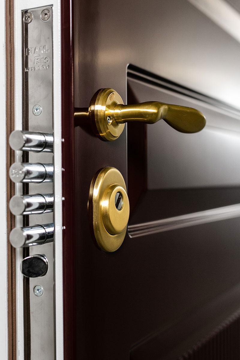 A close-up of a brown door with a gold handle and lock. The edge of the door shows a multi-bolt locking system, highlighting enhanced security features.